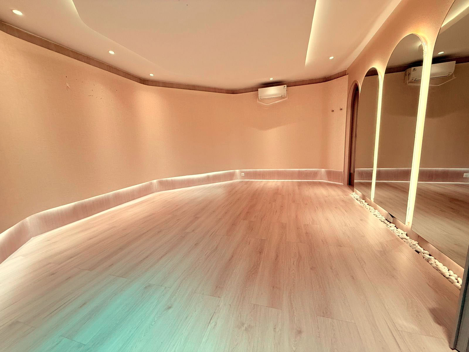 The mat and stretch studio with arched mirrors and warm wood floors